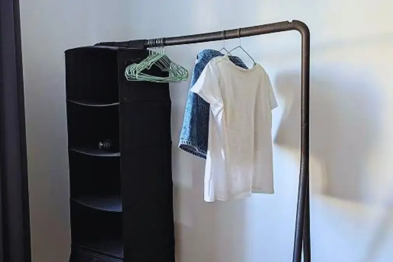 black metal clothing rack in small mens bedroom