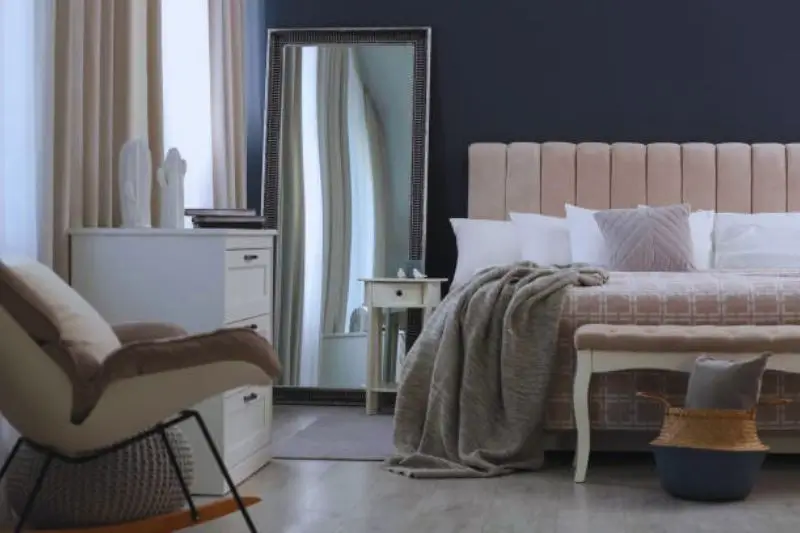 full length mirror reflecting window in small bedroom