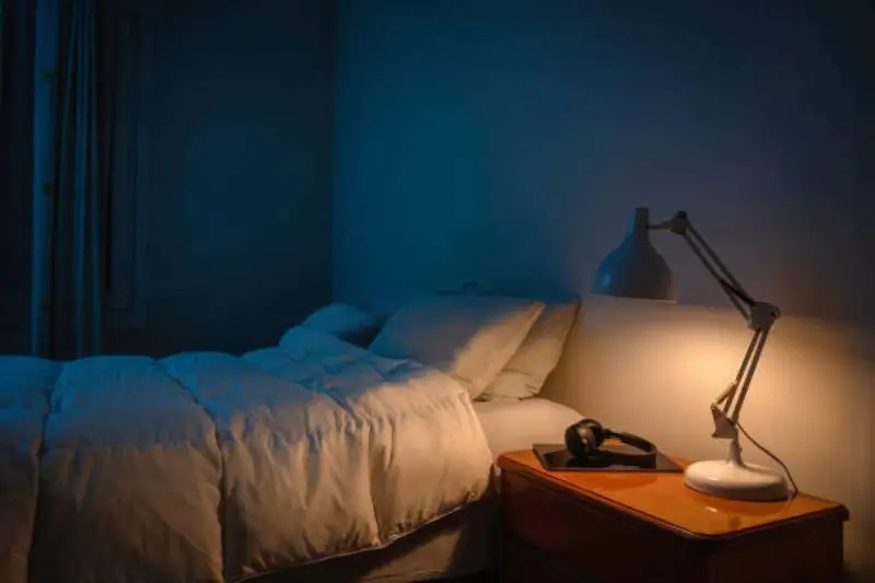 layered lighting with sconce and lamp in small mens bedroom