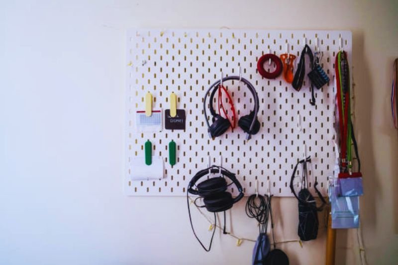pegboard organizer above desk in small mens bedroom