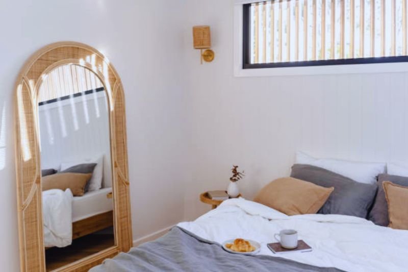 two arched mirrors on each side of bed in small bedroom