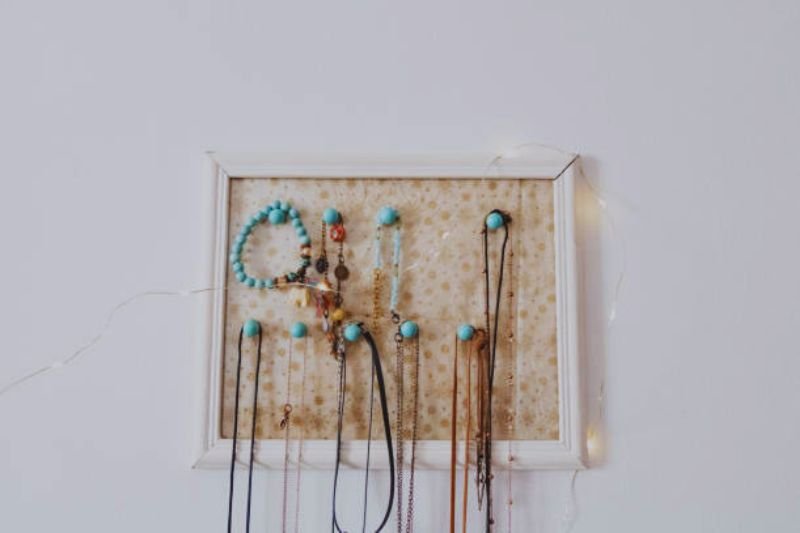 wall mounted jewelry bar with necklaces in small bedroom
