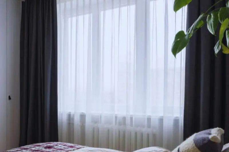 floor to ceiling linen curtains hung high in small bedroom
