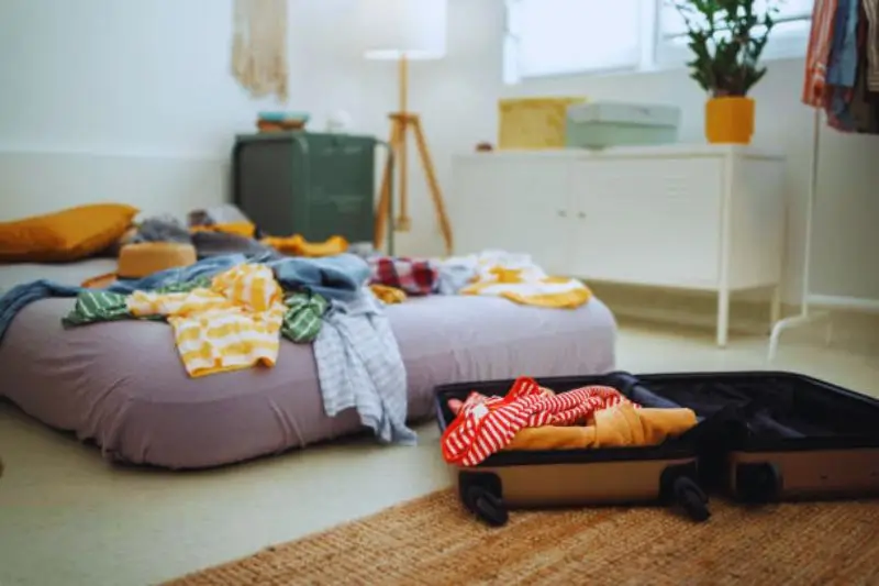 suitcase stored flat under bed with clothes inside