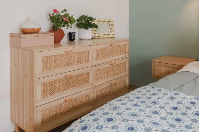 low wide dresser styled with lamp and plant in small bedroom
