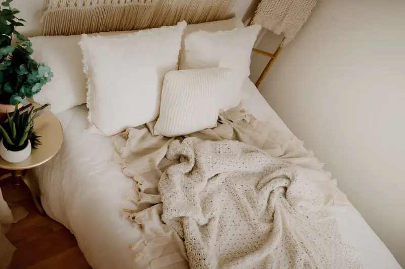 chunky knit throw and boucle pillow on bed in small bedroom