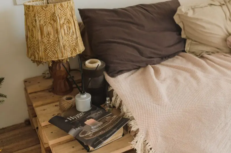 styled nightstand with lamp books and candle in small bedroom