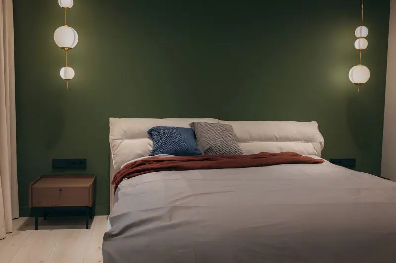 dark forest green accent wall behind bed in small bedroom
